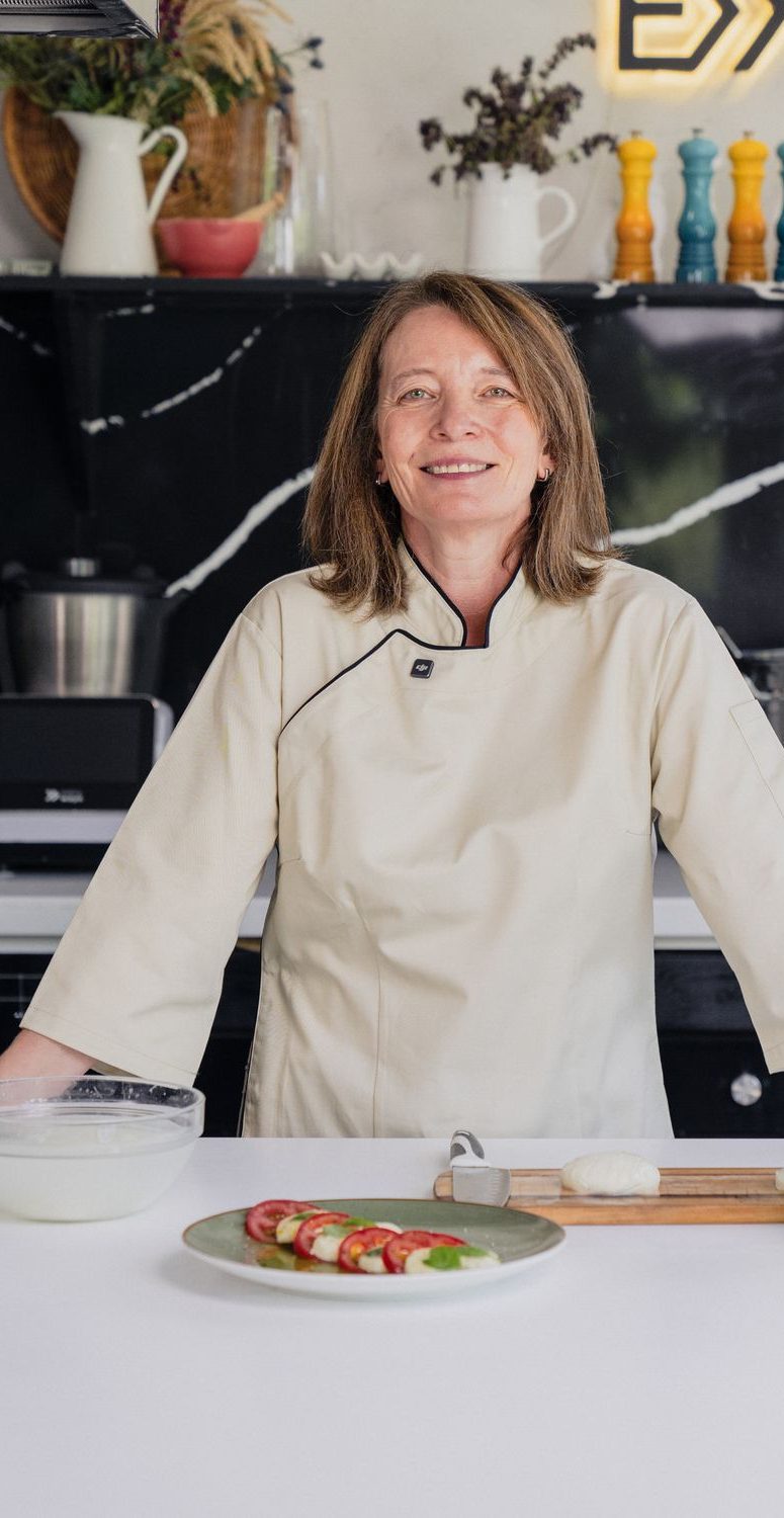 Bernardita Correa de brazos cruzados en su cocina de mesón blanco y mármol negro.
