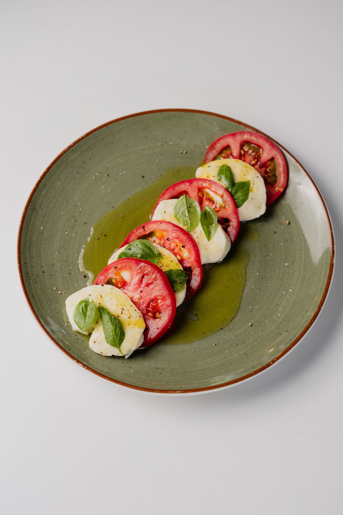Plato de caprese con mozzarella artesanal cortada en rodajas, tomate, albahaca y aceite de oliva.